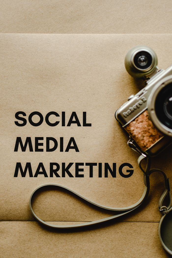 Gros plan sur un appareil photo vintage placé à côté d’un texte conceptuel sur le marketing des réseaux sociaux, sur fond brun.